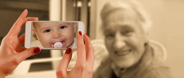 A smart phone with a picture of a baby, and an older lady in the background