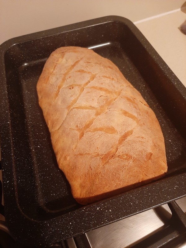 Delicious loaf of bread, fresh out of the oven in a pan, cooling down