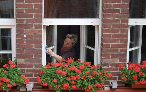 Lady cleaning window, choosing a home care provider