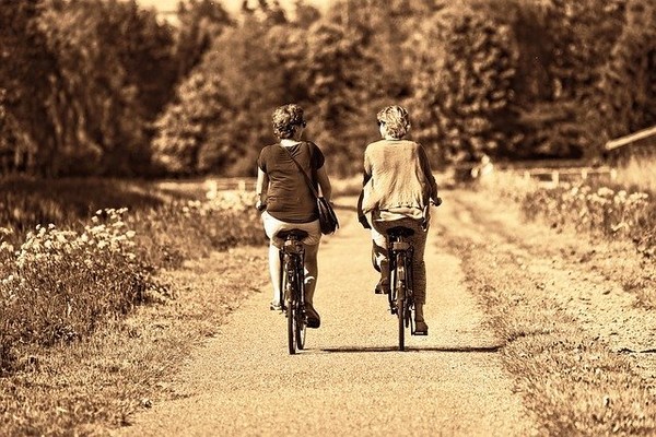 Couple cycling on bike down country lane, the power of friendship